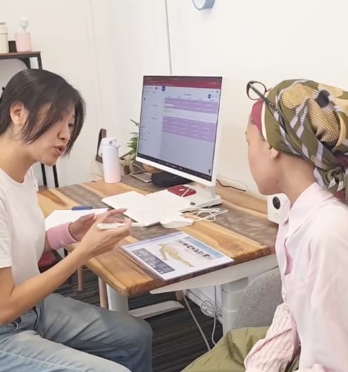 Dr Tao explaining findings using a spine chart during a patient consultation at Kirolounge